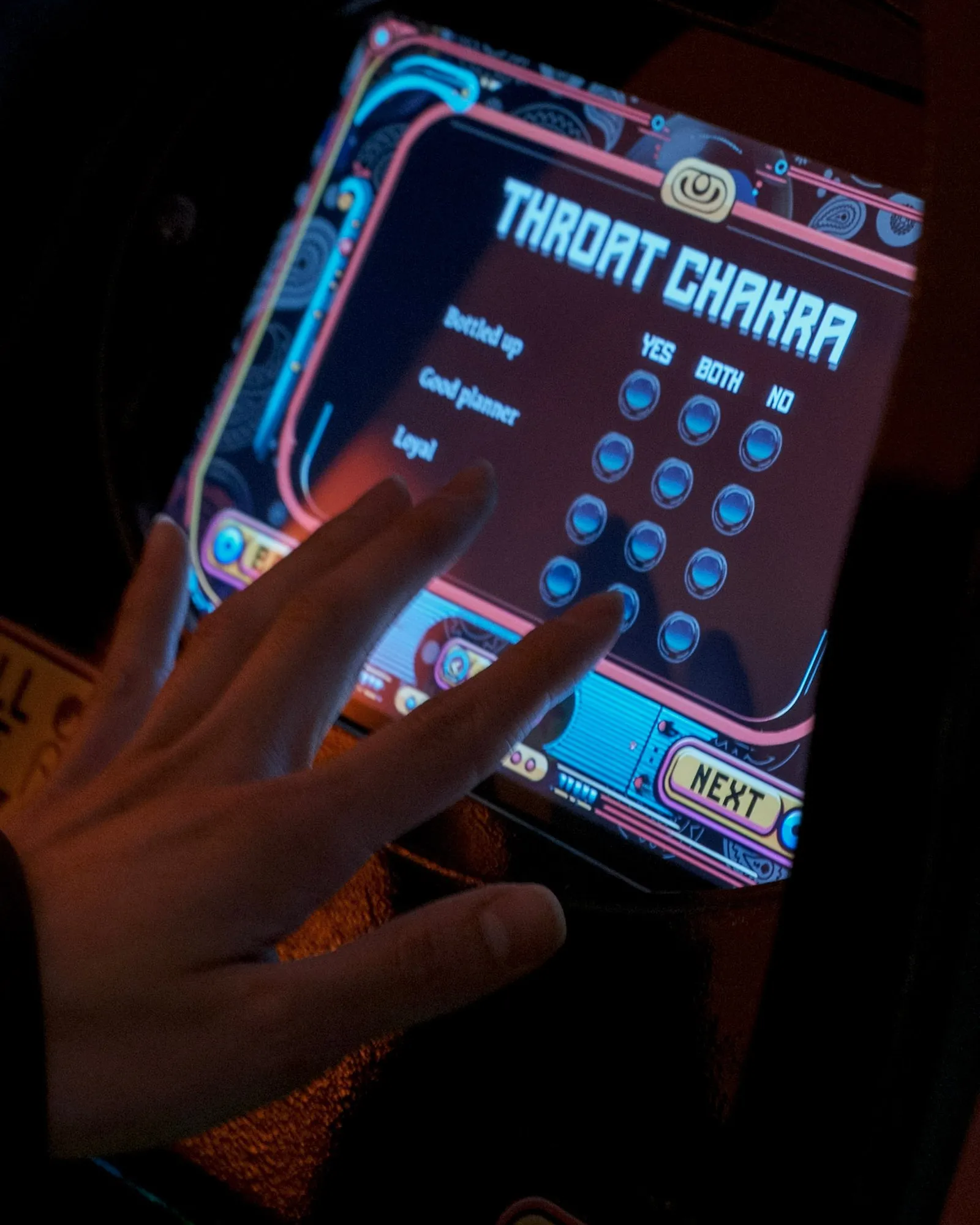 A hand on the touchscreen during the Throat Chakra question