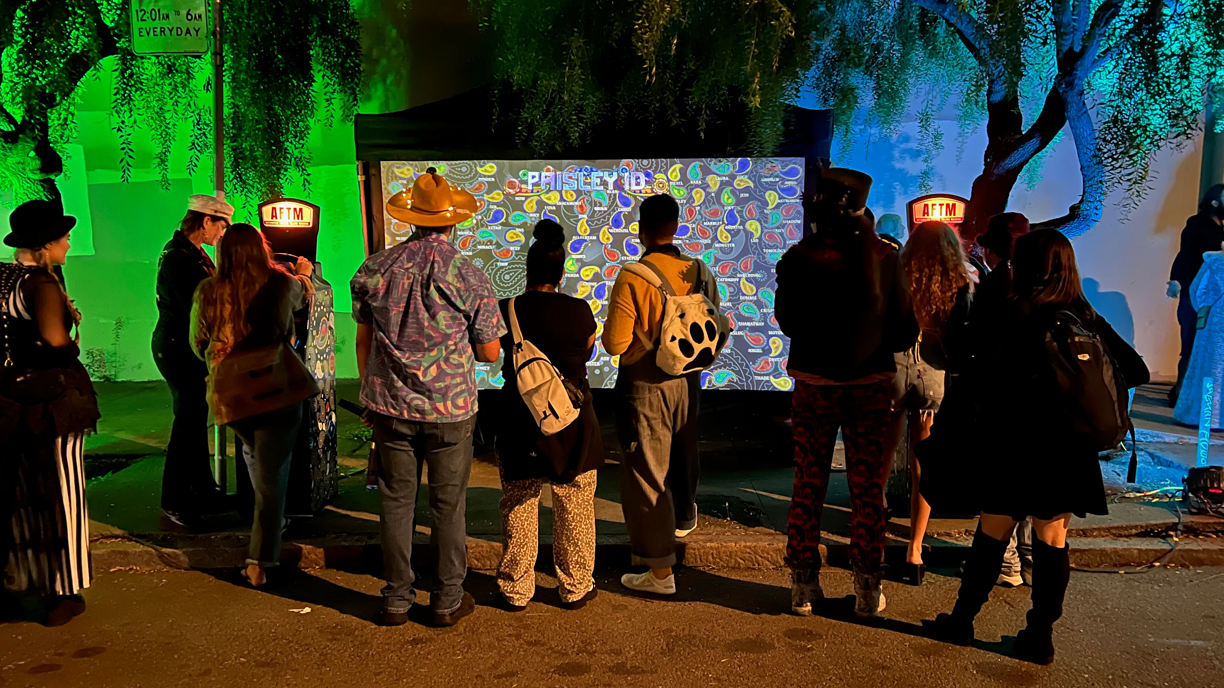 A crowd lined up in front of the aquarium projection at night, an AFTM glowing on each side